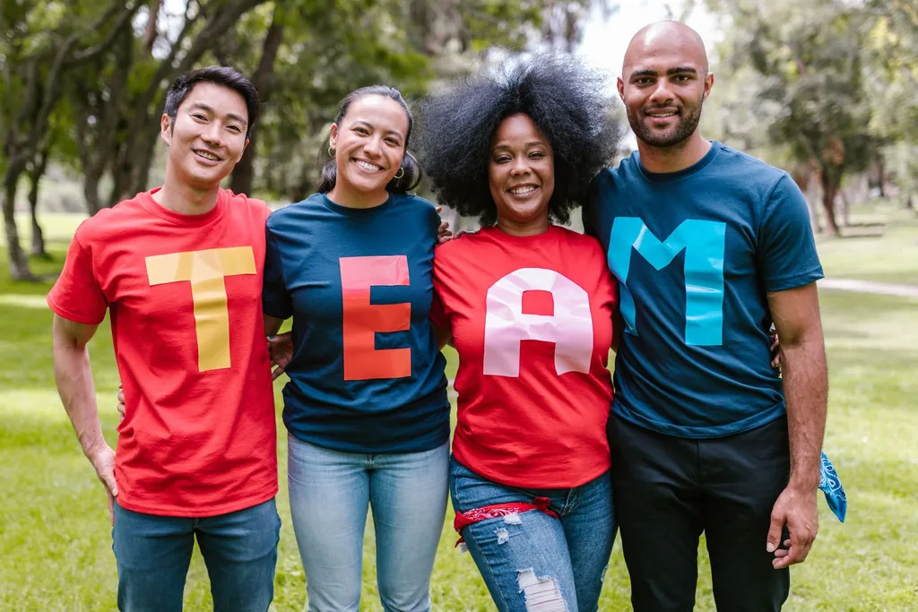Four people smiling together outdoors in colorful TEAM T-shirts